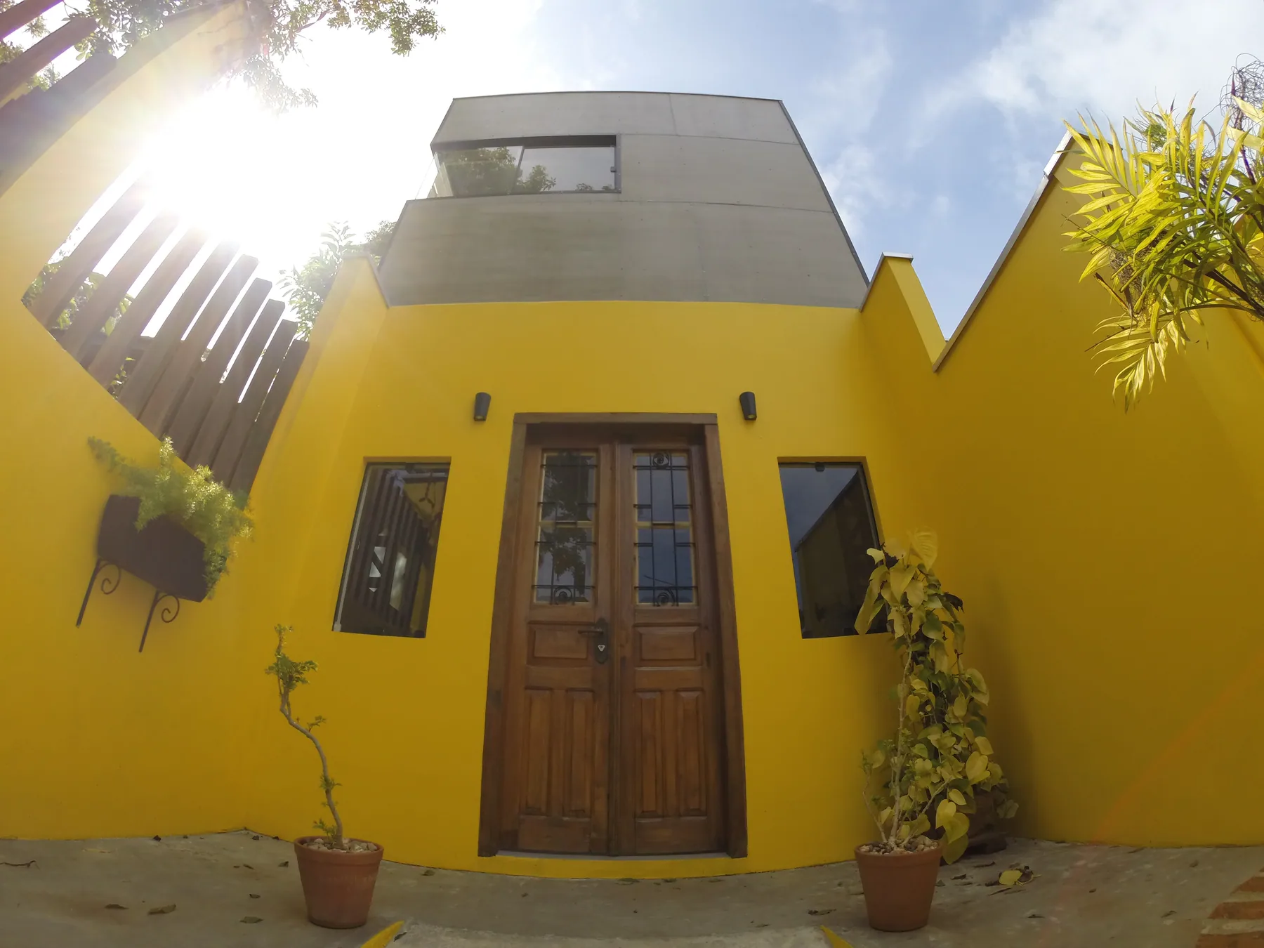 Entrada da Invista com fachada amarela e porta de madeira