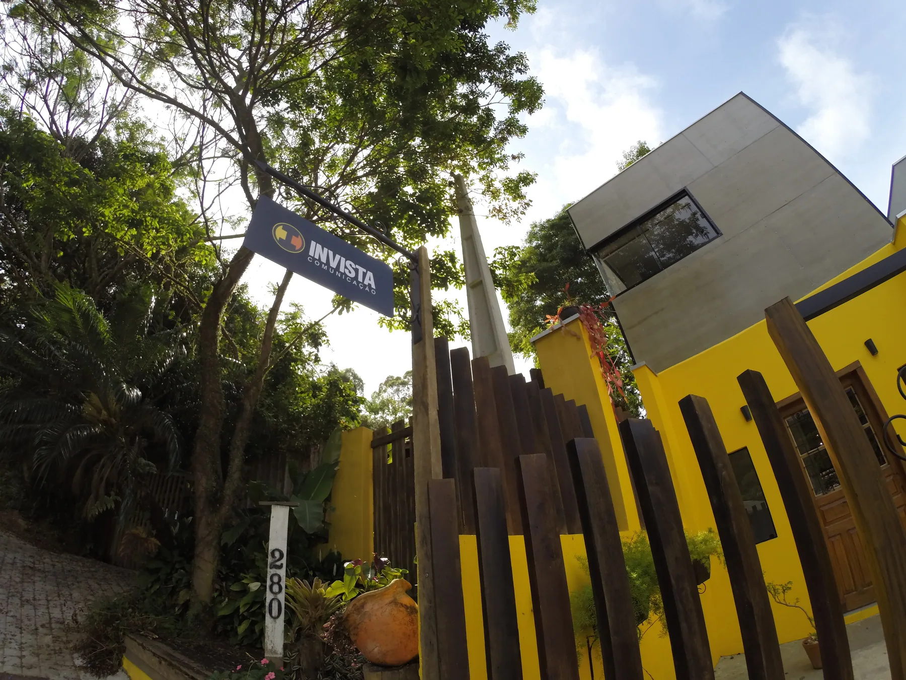 Fachada da Invista com placa da agência e jardim